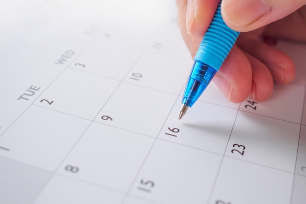 Main de femme avec stylo écrit sur la date du calendrier concept de réunion de rendez-vous de planification d'entreprise