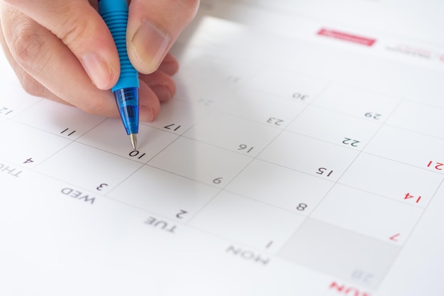 Main de femme avec stylo écrit sur la date du calendrier concept de réunion de rendez-vous de planification d'entreprise