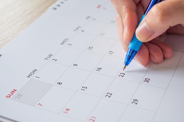 Main de femme avec stylo écrit sur la date du calendrier concept de réunion de rendez-vous de planification d'entreprise