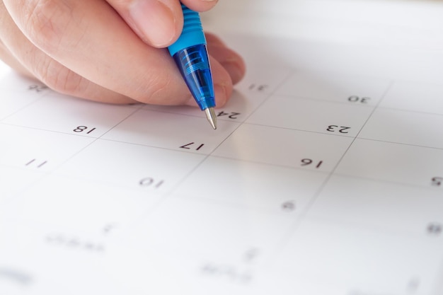 Main de femme avec stylo écrit sur la date du calendrier concept de réunion de rendez-vous de planification d'entreprise