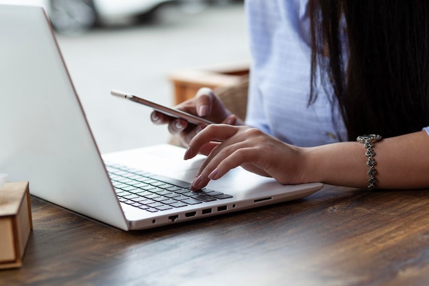 Main de femme téléphone et ordinateur au café