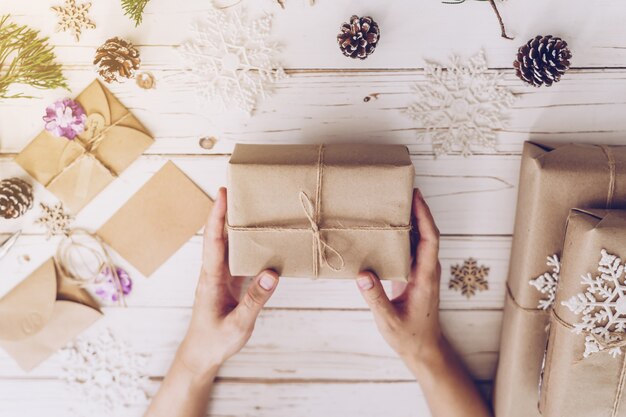 Main de femme tenant une belle boîte-cadeau de Noël à table