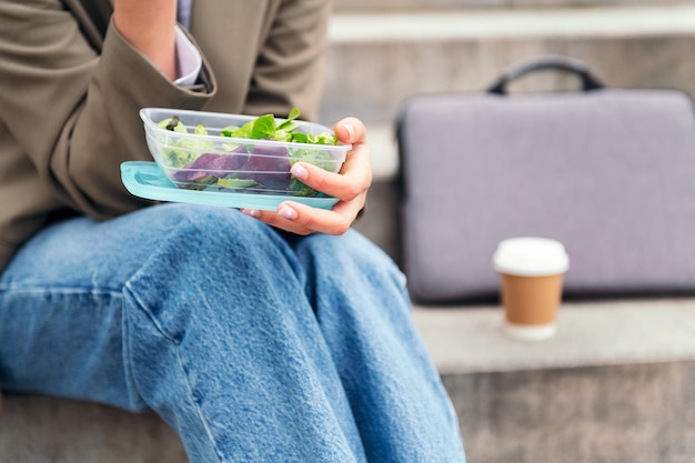 Main de femme tenant une boîte à lunch avec salade