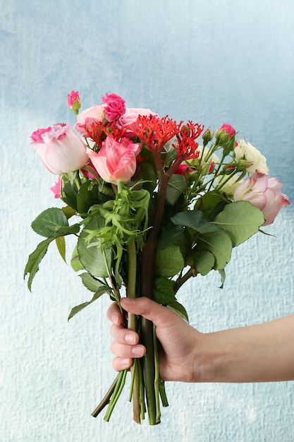 Main de femme tenant un bouquet de fleurs fraîches sur fond clair