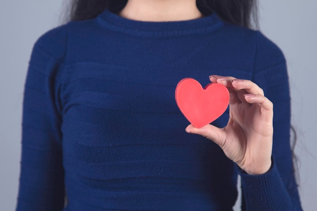 Main de femme tenant un coeur rouge