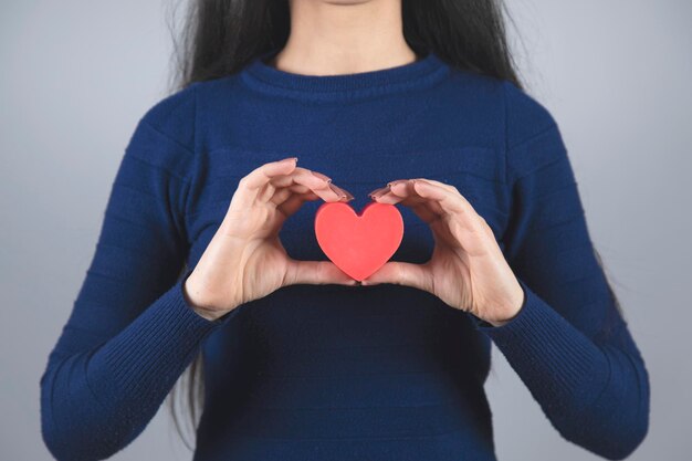 Main de femme tenant un coeur rouge