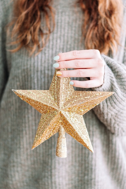 Main de femme tenant une décoration de Noël dorée