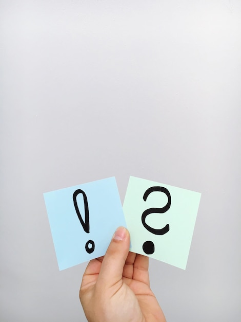 La main d'une femme tenant deux notes adhésives contenant des signes de ponctuation