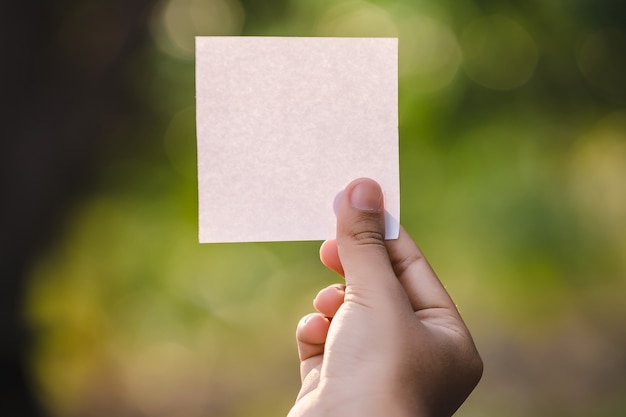 Main de femme tenant une feuille de papier vierge