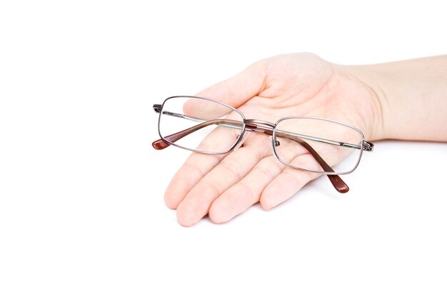 Main de femme tenant glasse sur fond blanc. Lunettes à la main