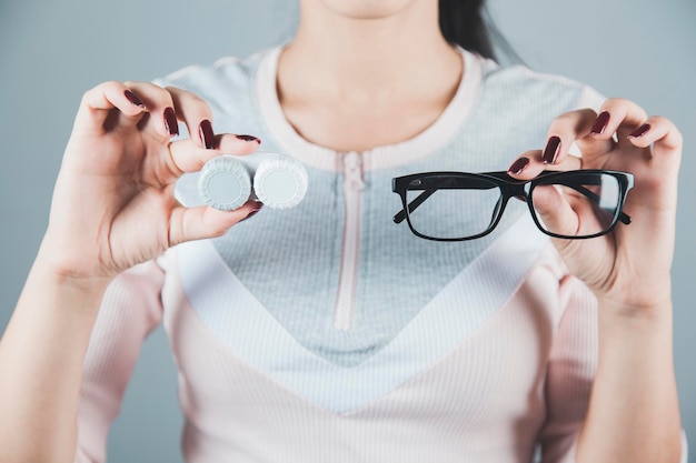 Main de femme tenant des lunettes avec des lentilles