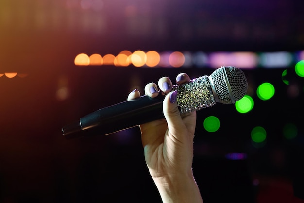 Main de femme tenant un microphone sans fil avec des strass sur scène