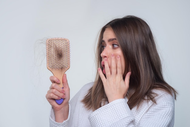 Main de femme tenant un peigne avec un grave problème de perte de cheveux pour le shampooing de soins de santé