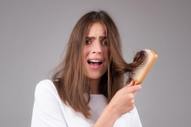 Main de femme tenant un peigne avec un grave problème de perte de cheveux pour le shampooing de soins de santé