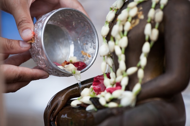 Main de femme tenant un petit bol pour se baigner Bouddha de cérémonie pour une cérémonie de bénédiction célébrant Songkran