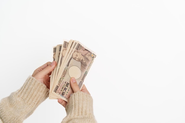 Main de femme tenant une pile de billets de banque en yens japonais Mille yens d'argent Japon trésorerie Récession fiscale Économie Inflation Financement des investissements et concepts de paiement des achats