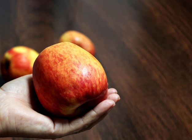 Main de femme tenant une pomme rouge