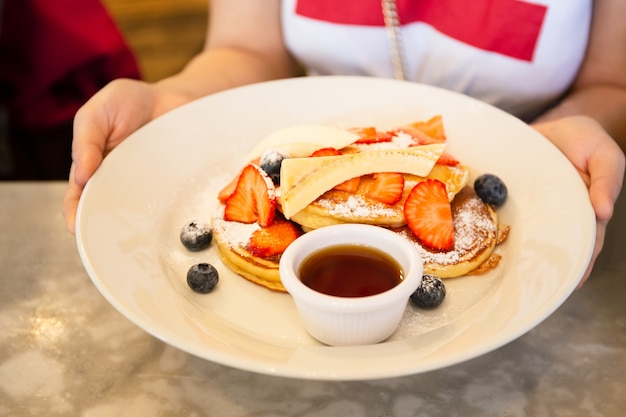 Main de femme tenant le repas de petit déjeuner de fruits mélangés et sirop d&#39;érable.