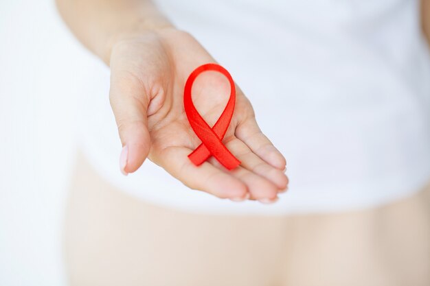 Main de femme tenant le ruban rouge VIH, ruban de sensibilisation à la journée mondiale du sida.