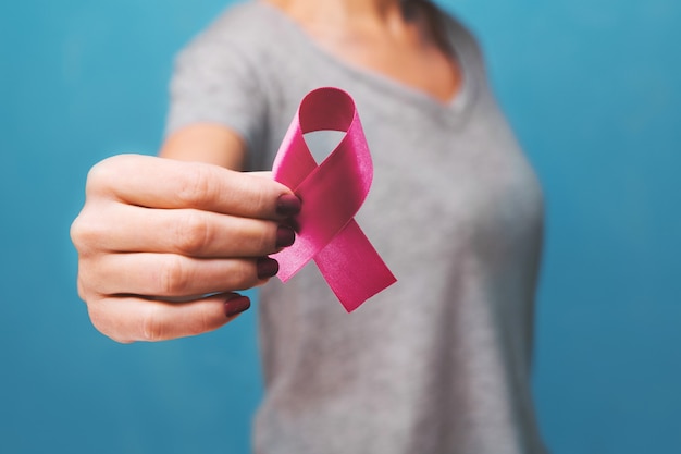 Main de femme tenant la sensibilisation au cancer du sein à ruban rose. concept de soins de santé et de médecine