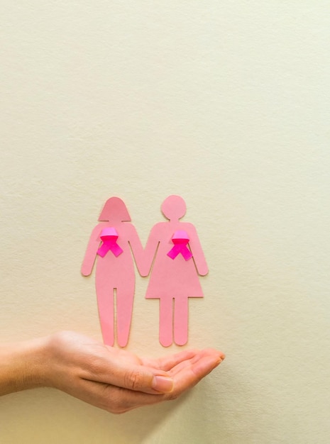 Main de femme tenant la silhouette de la fille avec ruban rose sensibilisation au cancer du sein Concept de la journée mondiale du cancer
