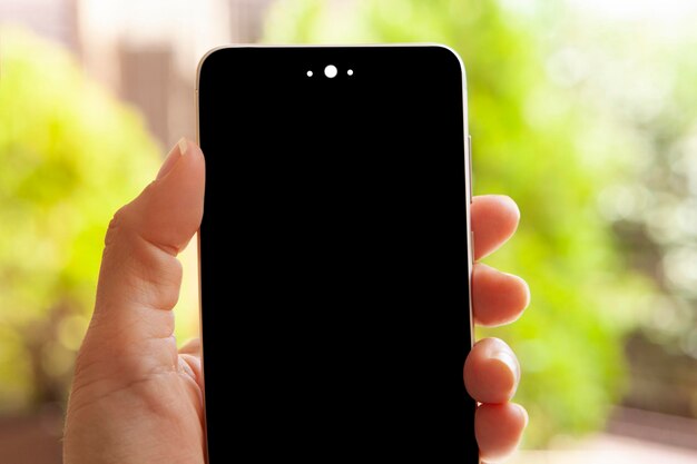 Main de femme tenant un smartphone avec écran noir