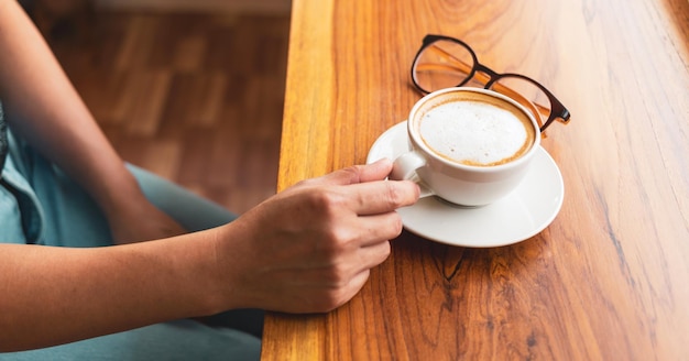 Main de femme tenant une tasse de café détendu dans un café