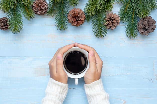 Main de femme tenant une tasse de café noire avec décoration de Noël, bonne année et vacances de Noël
