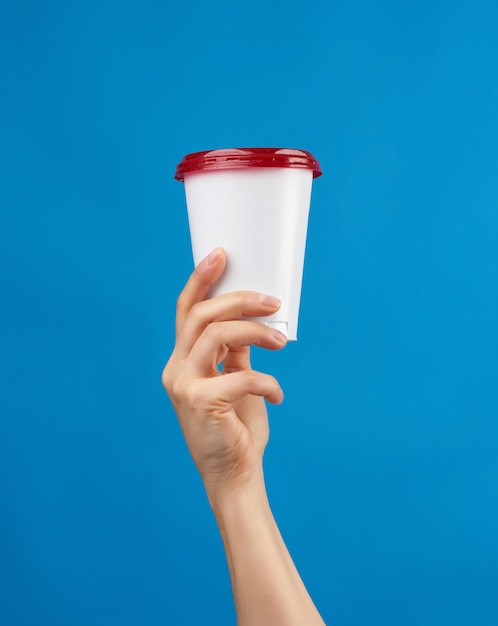 Main de femme tenant une tasse de papier jetable