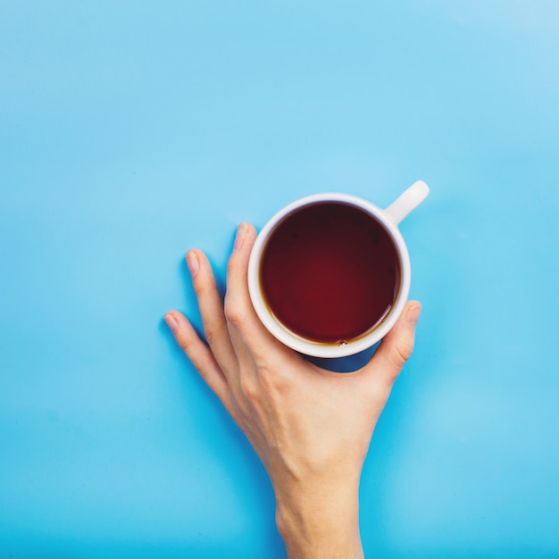 Photo main de femme tenant une tasse de thé ou de café chaud