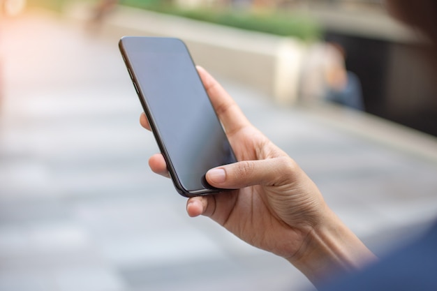 Main de femme tenant un téléphone intelligent avec l&#39;arrière-plan flou. mise au point sélective et mise au point douce.