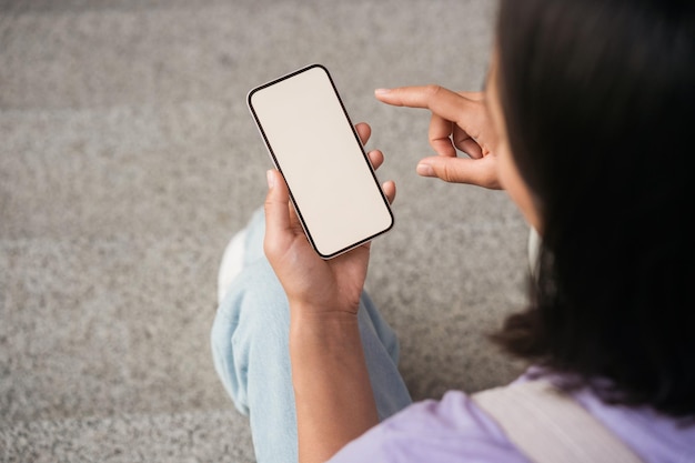 Main de femme tenant un téléphone mobile faisant des achats en ligne en regardant un écran vide. Femme utilisant une application mobile