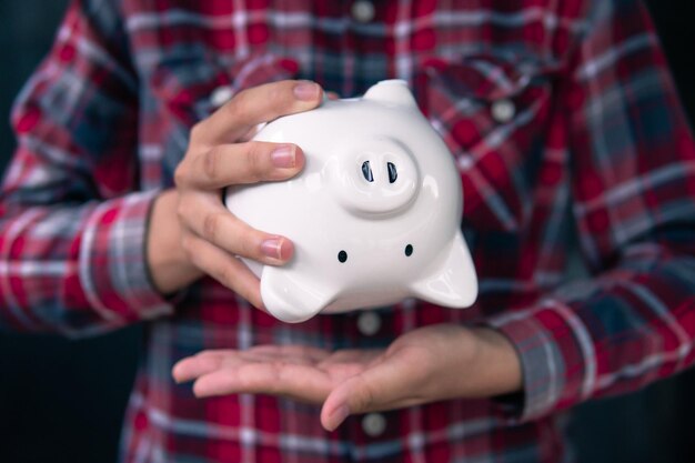 Main de femme tenant une tirelire blanche pour économiser de l'argent financier conceptbudget