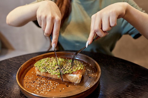 Main de femme tenant un toast à l'avocat sain