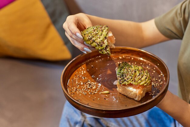 Main de femme tenant un toast à l'avocat sain