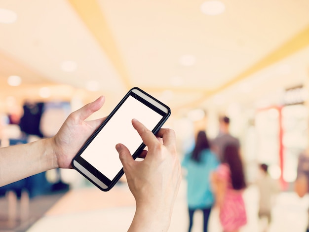 Main femme tenant et en utilisant le téléphone avec l&#39;arrière-plan flou au centre commercial.