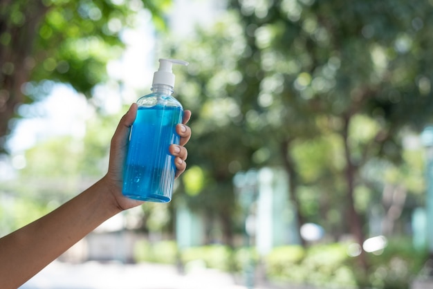 Main de femme tenir le gel pour les mains alcool désinfectant bleu pour protéger le coronavirus