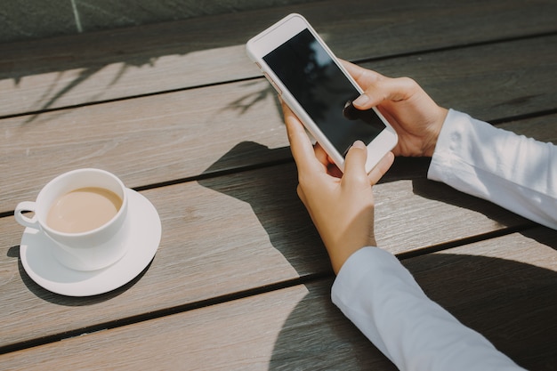 Main de femme textos pour quelqu'un avec écran noir au café