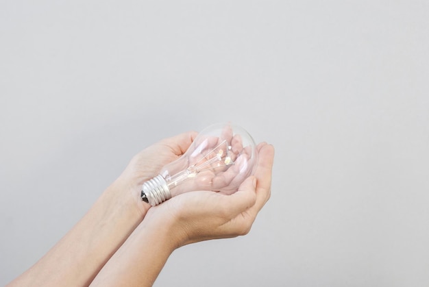 La main d'une femme tient une ampoule électrique à incandescence Création d'une idée Technologies