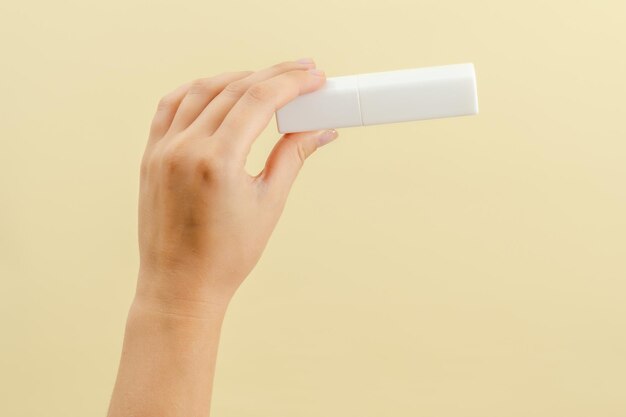 La main de la femme tient une bataille de crème de tube blanc pour les produits cosmétiques isolés sur fond clair