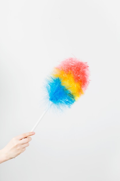 Main de femme tient une brosse pour nettoyer la poussière sur le mur gris