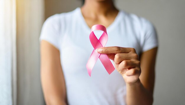 La main d'une femme tient un ruban rose symbolisant la sensibilisation au cancer du sein et les soins médicaux