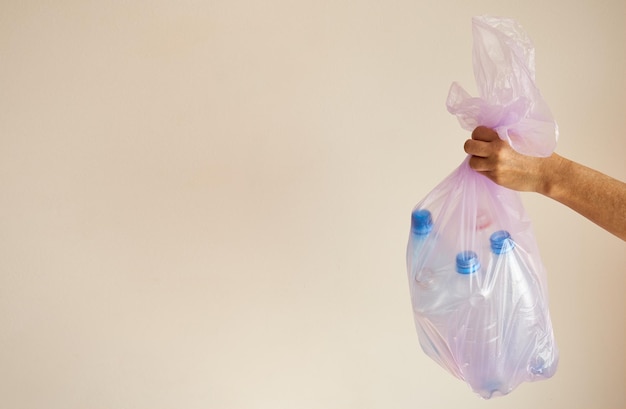 La main de la femme tient un sac poubelle avec des bouteilles en plastique copiez l'espace pour la publicité