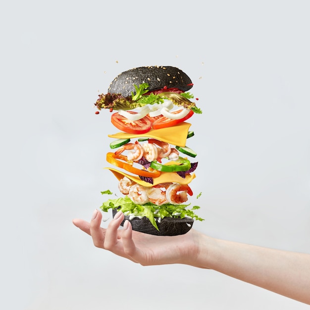 La main de la femme tient un sandwich sain à base de fruits de mer et de légumes frais sur fond clair