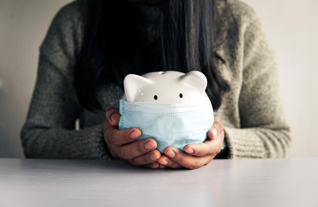 Main de femme et tirelire blanche pour économiser de l'argent concept budget financier