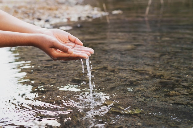 Main de femme touchant l'eau au milieu de la nature