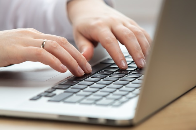 Main de femme travaillant sur un ordinateur portable à l'aide du pavé tactile