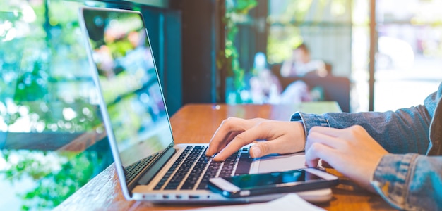 Main de femme travaillant sur un ordinateur portable au bureau.