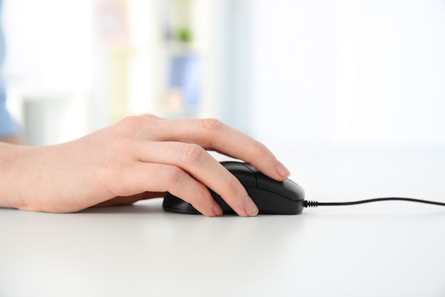 Main de femme travaillant avec une souris d'ordinateur au bureau