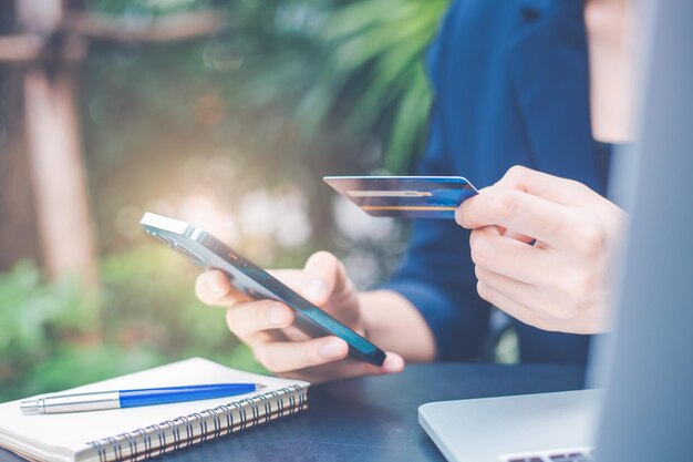 Photo la main de la femme utilise un téléphone portable et une carte de crédit pour gérer les achats en ligne